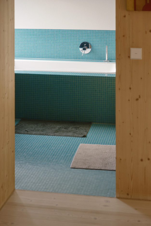 The shade between blue and green and the small tiles in the bathroom contrast with the light wood interior. (Photo: Jan Hanrion/Paperjam)