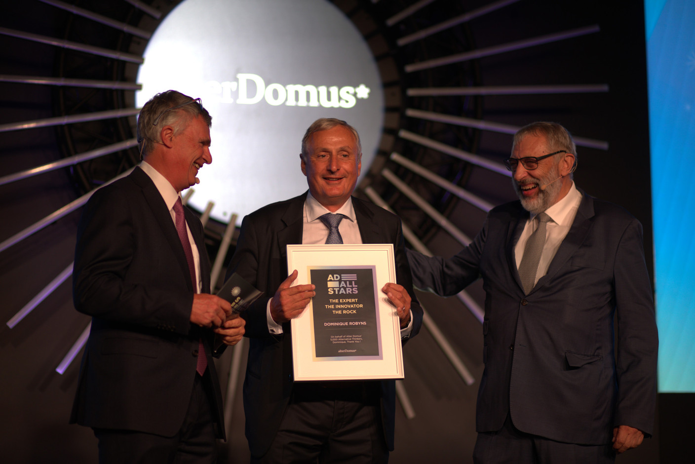 Dominique Robyns (centre), Alter Domus founder, receiving an award of honour from René Beltjens and Gérard Becquer, members of Alter Domus’ supervisory board. Photo: Alter Domus