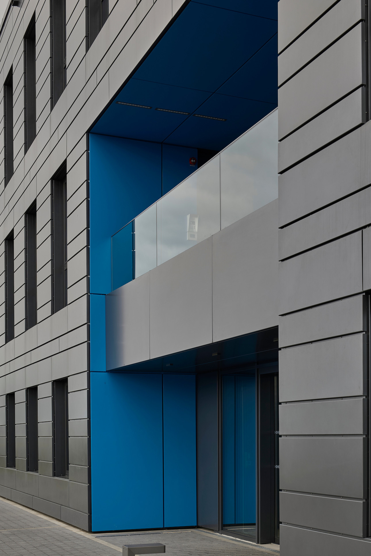 L’entrée du bâtiment est signalée par un volume évidé aux parois bleues qui contrastent avec le reste de la façade. (Photo: Eric Chenal)