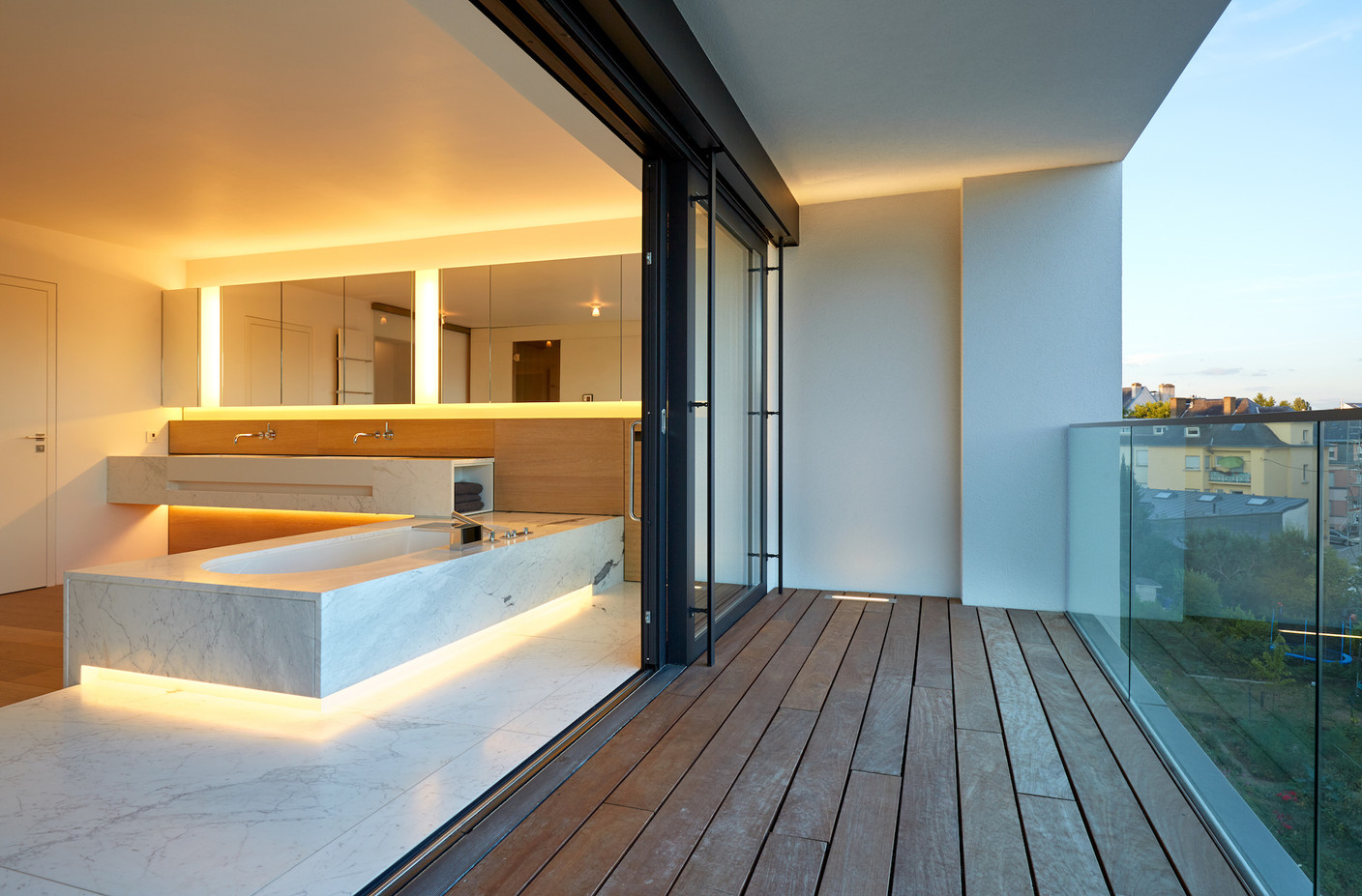 Dans cette salle de bains dessinée par NJOY, on trouve à la fois un éclairage soutenu au niveau du miroir, un éclairage indirect plus doux pour l’ambiance, et un spot intégré dans le sol de la terrasse pour prolonger la perception de l’espace. (Photo: Christof Weber)