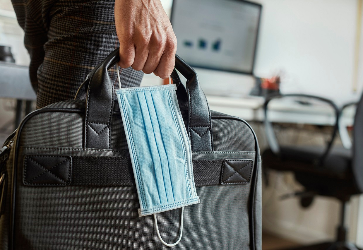 Closeup of a young man in an office holding a briefcase and a surgical mask in his hand (Photo: Lyxor ETF)