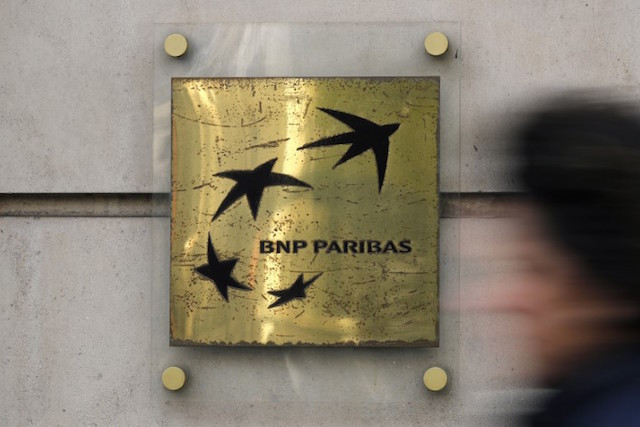 A man walks past a BNP Paribas bank sign on an office building in Paris, on 3 March 2016 Reuters/Christian Hartmann