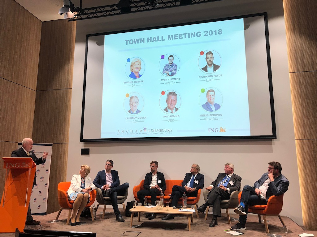 Paul Schonenberg at the podium asks a question of candidates Simone Beissel (DP), Sven Clement (Pirates), Franz Fayot (LSAP), Laurent Mosar (CSV), Roy Reding (ADR) and Meris Sehovic (Greens). Amcham’s election town hall meeting took place at ING House on 27 September 2018 Duncan Roberts
