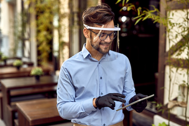 A waiter is pictured wearing a visor. Under the covid law amendment, people wearing just visors in a place where a mask must be worn could be fined Shutterstock