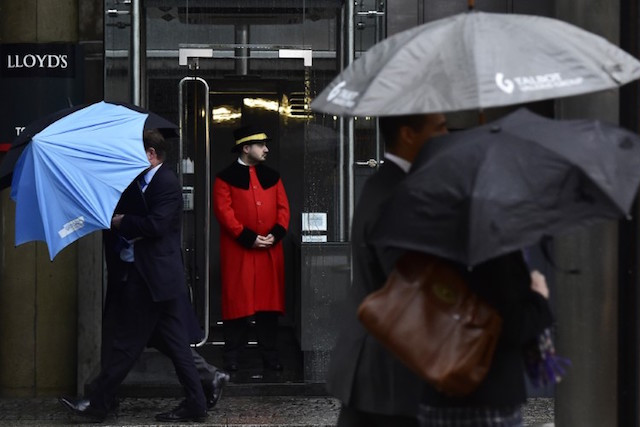 A doorman looks out as workers walk in the rain past the Lloyd’s of London building in the City of London, on 7 January 2016 REUTERS/Toby Melville