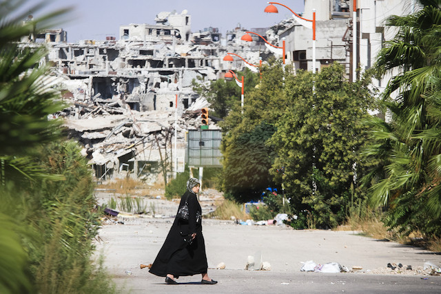Illustration photo. 2013 archive photo shows a woman walking down a street in Homs, Syria, with destroyed buildings in the background Shutterstock