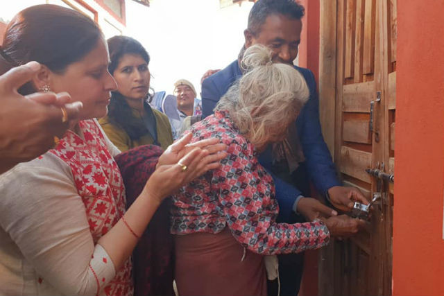 A 106-year-old woman unlocks the front door of her new home in Sindhupalchowk district, which was rebuilt through an AEIN project AEIN