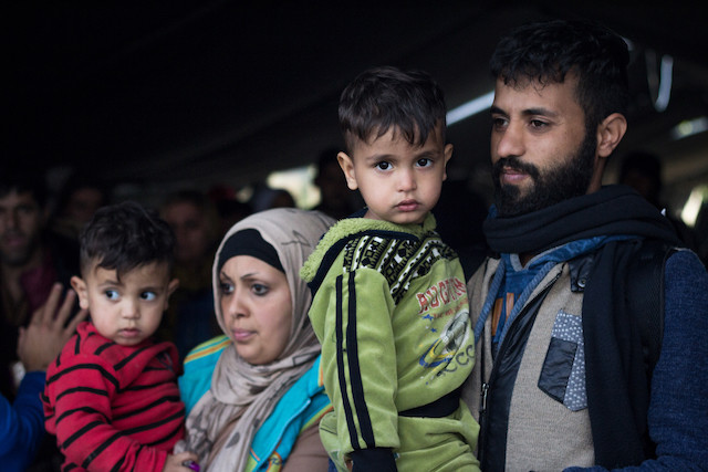 2015 photo shows a man and woman holding children waiting to cross the Serbia-Croatia border on the Balkans route Shutterstock