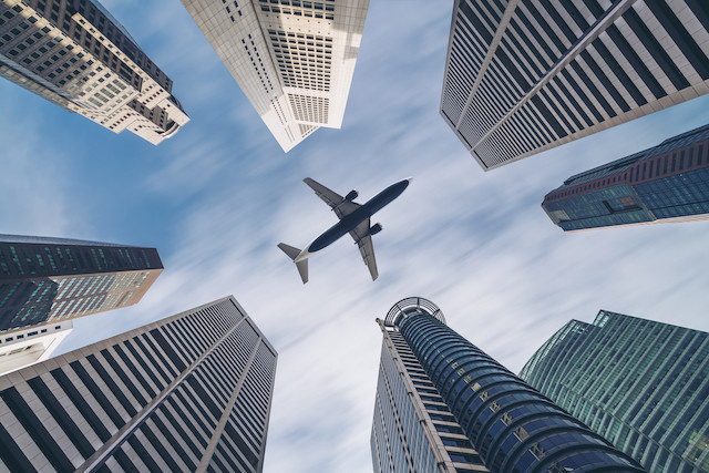 Jet plane aircraft traveling in the sky over city buildings in downtown travel destination of Singapore City. Shutterstock