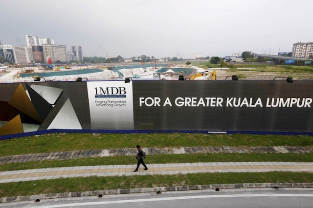 A man walks past a 1 Malaysia Development Berhad billboard at the fund’s flagship Tun Razak Exchange development in Kuala Lumpur, on 1 March 2015 Reuters/Olivia Harris