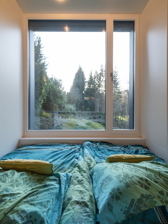 Depuis le lit des parents, la fenêtre ouvre la vue sur le jardin et sa verdure. (Photo: Guy Wolff/Maison Moderne)