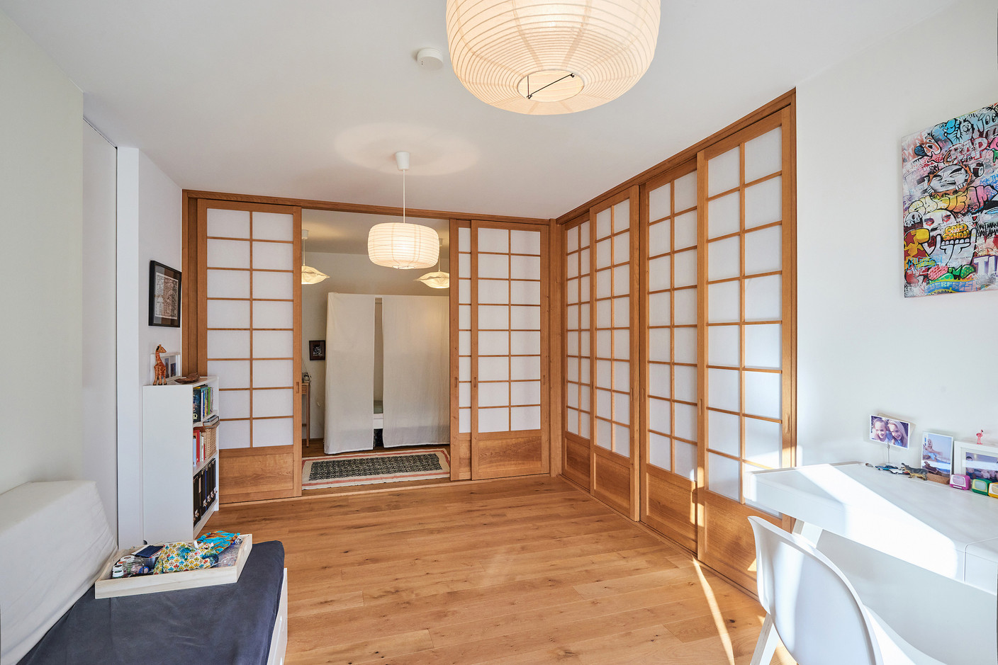 Au rez-de-chaussée, un espace à l’esprit minimaliste sert de pièce multifonctionnelle. Derrière des parois coulissantes d’inspiration japonaise se dissimulent buanderie, chambres des enfants, placards… (Photo: Andrés Lejona/Maison Moderne)