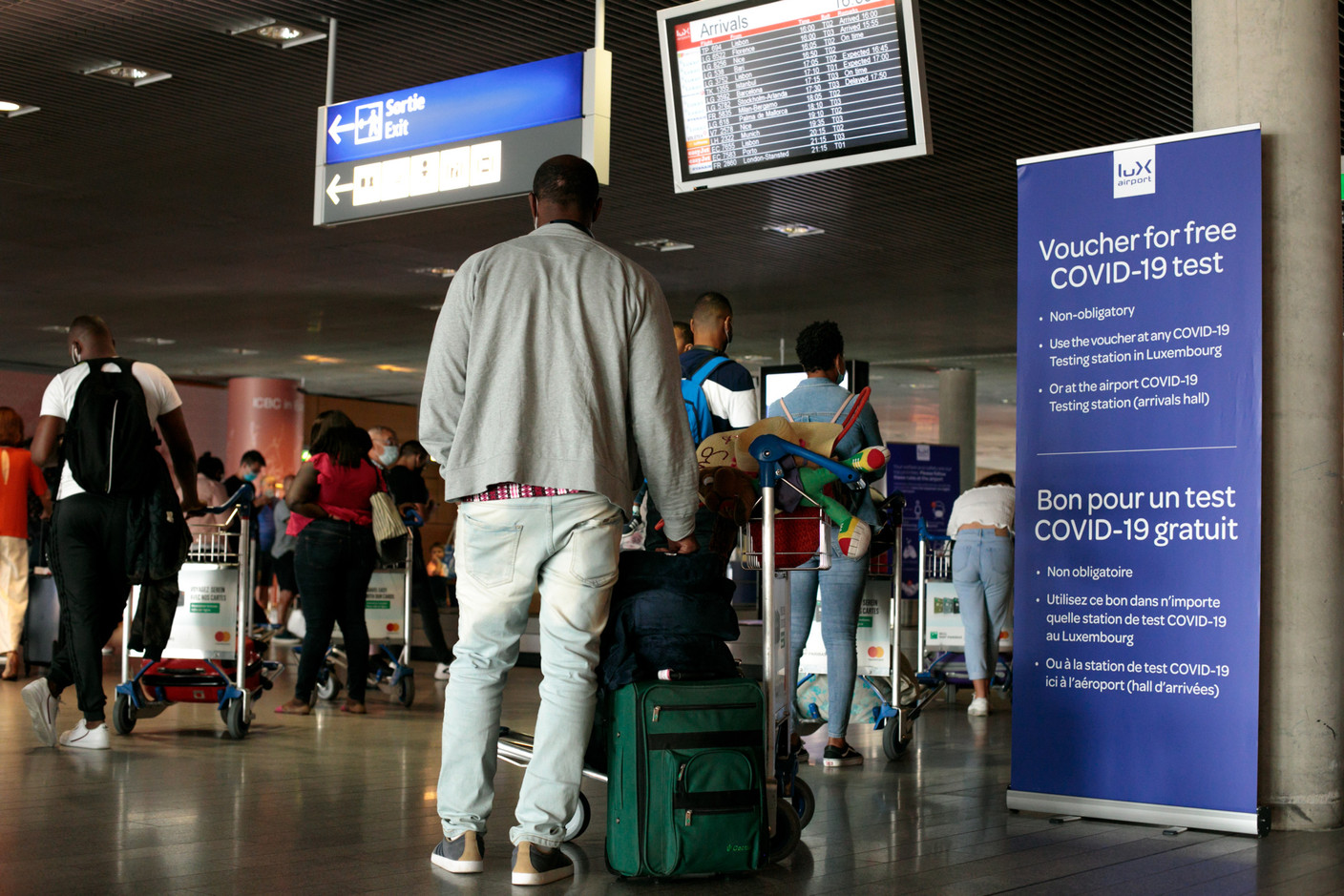 Masqués et à distance, les passagers attendent leurs bagages. (Photo: Matic Zorman / Maison Moderne)