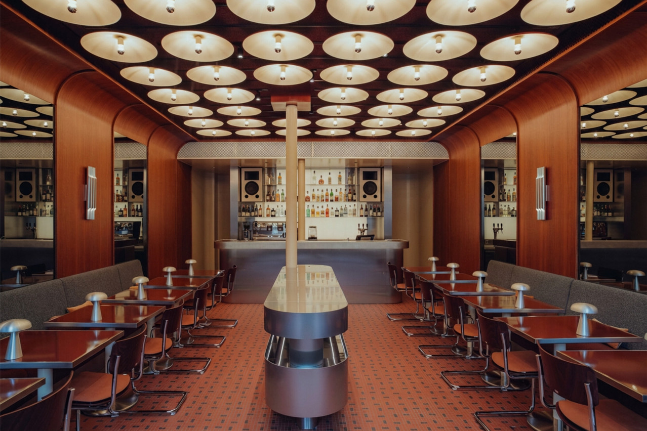 Curved Orient-Express panelling, a retro-futuristic stainless steel bar, and a mesmerising illuminated ceiling: the Café de Paris has reopened on Place d’Armes in a setting designed by Njoy. (Photo: Sebastian Madlener)