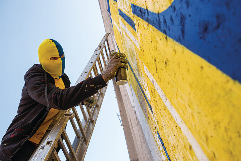 Spike working on piece wearing a balaclava in the colours of the Fat Cap Kings, one of the fictitious Ultras clubs he created for the project Spike