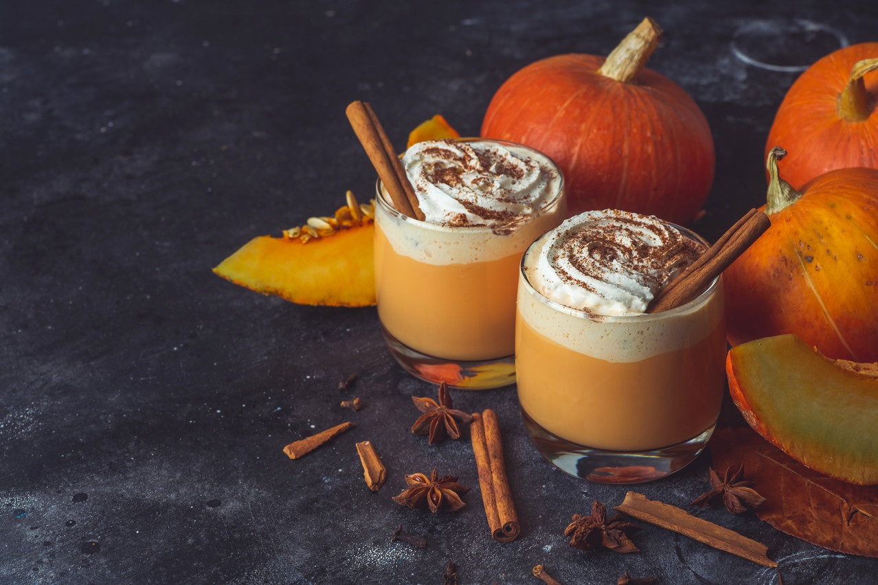 Autumn coffee with spicy pumpkin flavor and cream on a dark background. vovidzha/Shutterstock.
