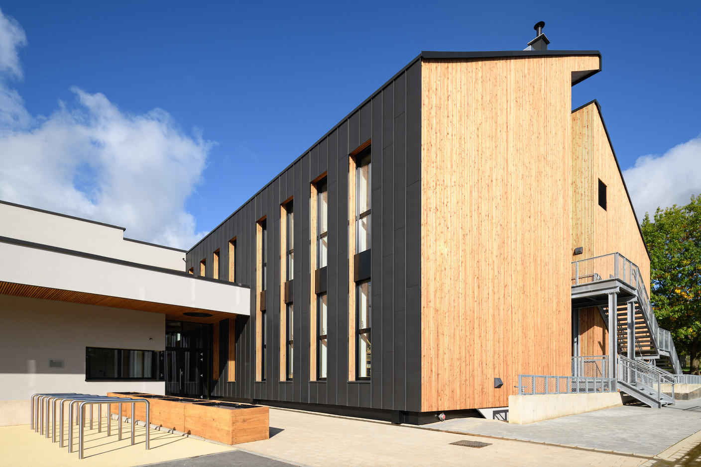 Le bâtiment haut a reçu un bardage de zinc et de bois qui contraste avec le bâtiment bas dont la façade est en crépis. (Photo: Julien Swol)
