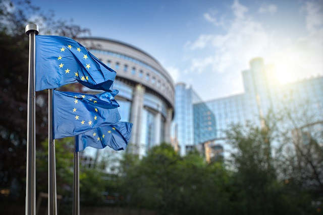 European Union flag against parliament in Brussels, Belgium. (Photo: artJazz)