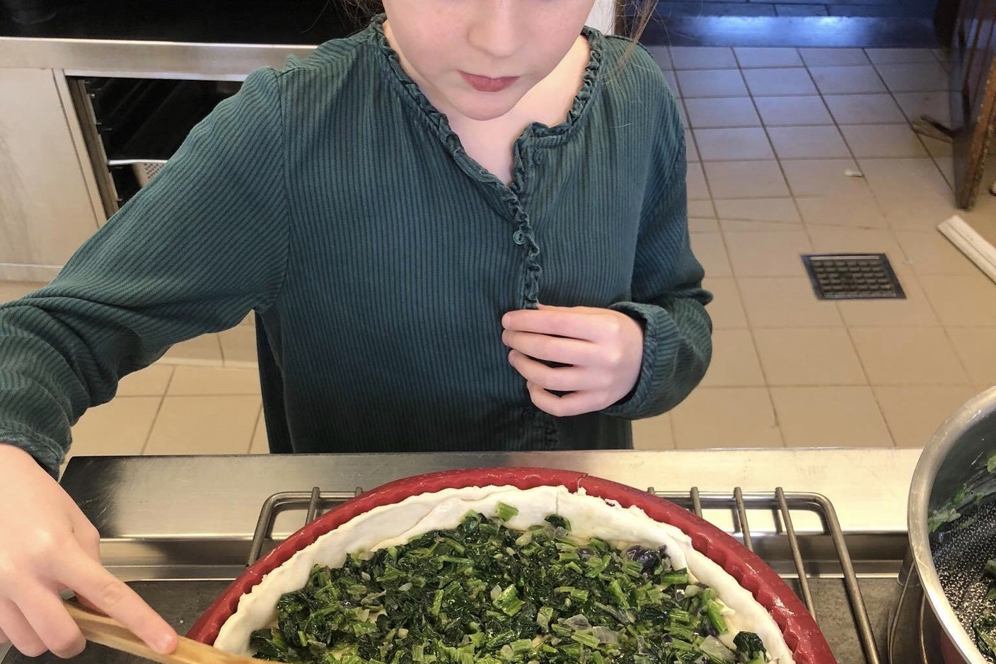 Louise, la fille du chef René Mathieu, nous apprend à faire sa tarte aux herbes sauvages préférée. Étape 4: elle dispose les feuilles qu’elle a fait revenir au préalable sur son fond de tarte. (Photo: René Mathieu)