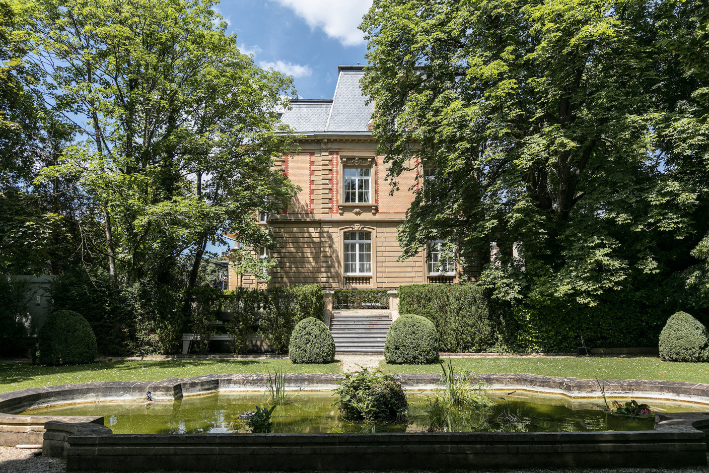 Une vue de la villa depuis le banc de pierre surplombant l’étang. (Photo: Romain Gamba/Maison Moderne)