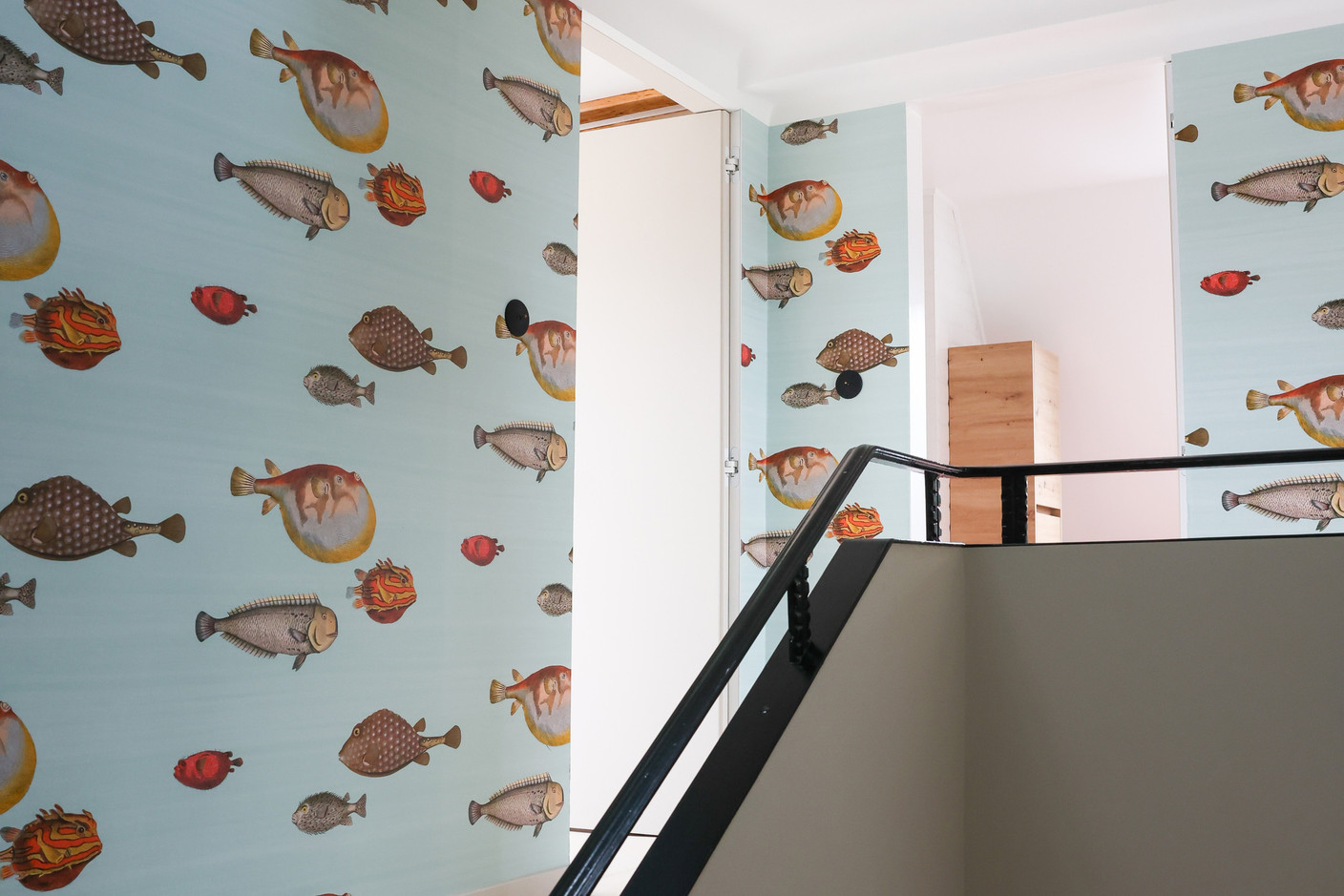 In the stairwell, wallpaper decorated with a “school of fish” brightens up the space, which is generously lit by a skylight. Photo: Marie Russillo/Maison Moderne