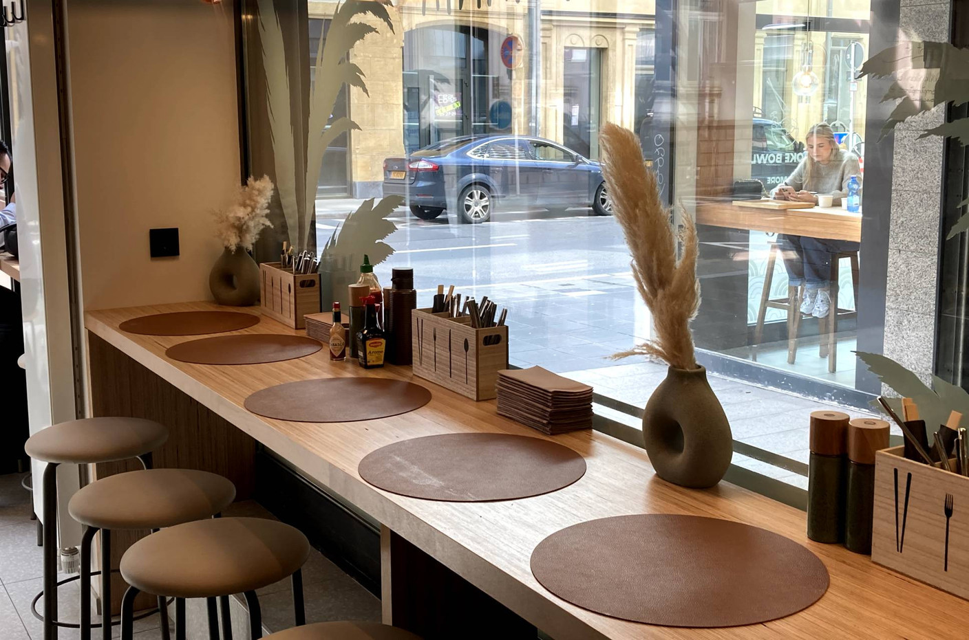 Une assise haute a été positionnée le long de la vitrine et est complétée par quelques tables dans le fond de la salle. (Photo: Paperjam.lu)