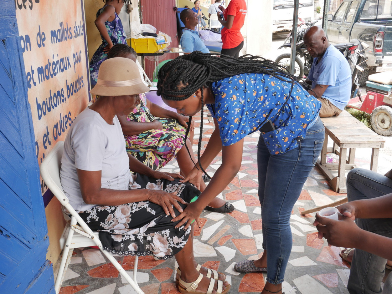 Les Cayes: the rehabilitation centre was damaged by the earthquake on 14 August. The building is still standing but it can’t be used and the rehabilitation team is working on the pavement outside. This woman had a stroke because of the psychological stress of the quake. Rawley Crews / HI