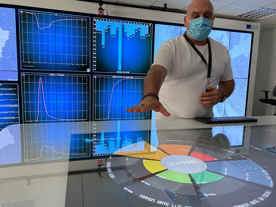 Au second plan, 25 écrans interactifs réunis pour former un mur de 7 mètres sur deux, qui réunissent toute une série d’informations. Au premier plan, une table interactive, sorte de poste de pilotage. En jouant sur le niveau de couleur de chacun des sept indicateurs, la machine élabore des scénarios, a expliqué Luc Vandenabeele (List). (Photo: Paperjam)