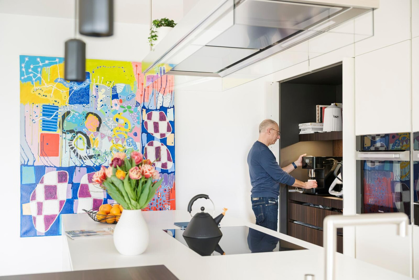 A minimalist kitchen with discreet storage, enhanced by a painting by Frank Jons, selected in situ, which brings colour and vibrancy to this refined space. (Photo: Jan Hanrion/Paperjam)